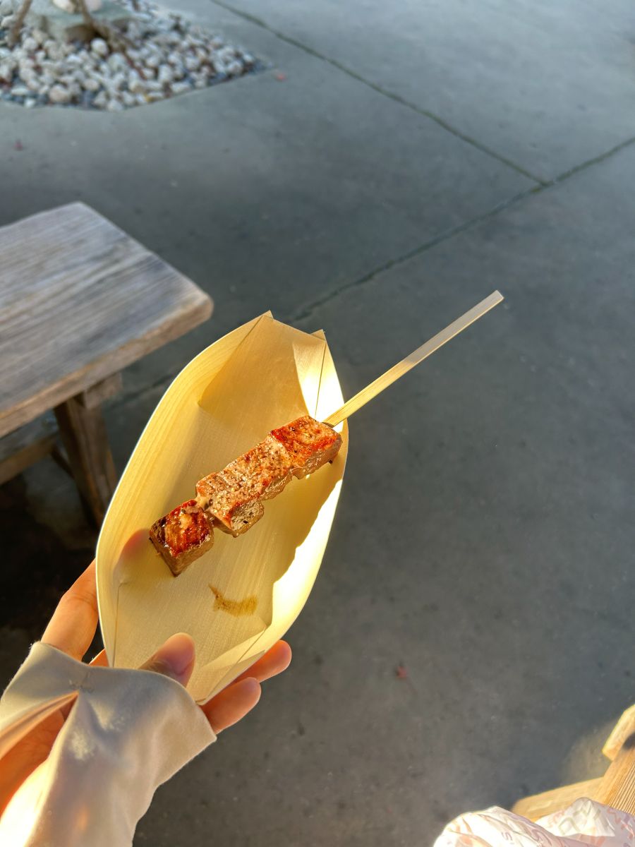 経木の舟に入った松阪牛の串焼きを手に持って食べ歩き(筆者撮影)